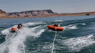 Two People In Tubes Are Being Pulled By A Boat GIF