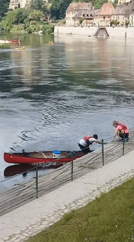 Two People Pulling A Canoe Out Of The Water GIF