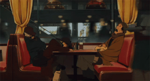 Two People Sit At A Table In A Diner With A Sign That Says Photo Shop In The Background GIF