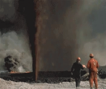 two people standing in front of a large flame