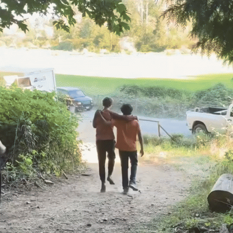 Two People Walking Down A Dirt Path With A White Truck Parked Behind Them That Says ' A ' On It GIF