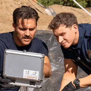 two police officers are looking at a case with a warning sticker on it
