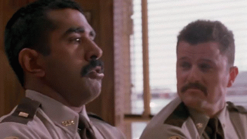 Two Police Officers Are Sitting Next To Each Other In A Room And Talking To Each Other . GIF