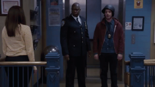 Two Police Officers Giving Each Other A Fist Bump In Front Of An Elevator GIF