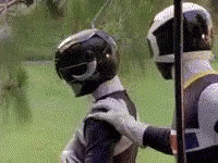 Two Power Rangers Are Standing Next To Each Other On A Field . GIF