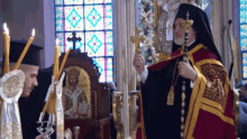 Two Priests Are Standing In Front Of A Stained Glass Window Holding Crosses And Candles GIF
