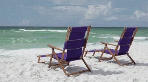 Two Purple Beach Chairs Sit On A Sandy Beach GIF