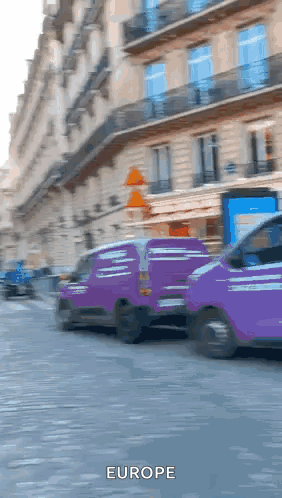 Two Purple Vans Are Driving Down A Street And The Word Europe Is On The Bottom Right GIF