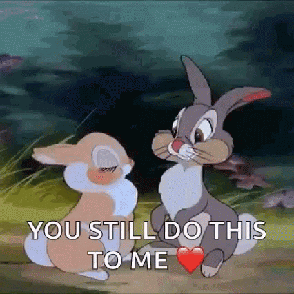 Two Rabbits Sitting With One Holding Heart In Mouth GIF