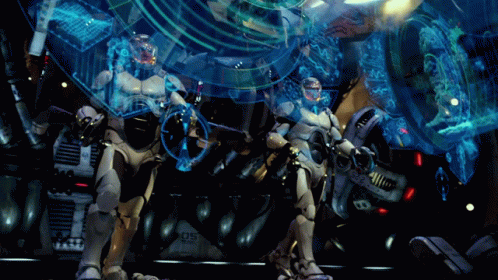 Two Robots Are Standing In Front Of A Machine With The Number 05 On It GIF