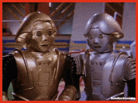 Two Robots Are Standing Next To Each Other And Looking At The Camera GIF