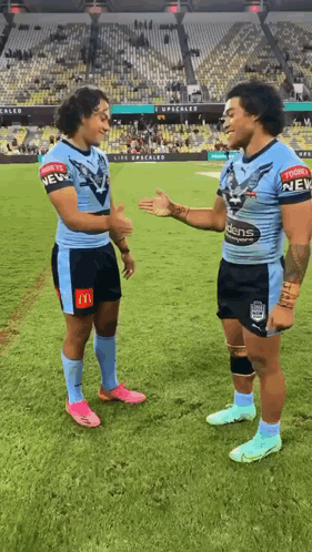 Two Rugby Players On A Field With One Wearing A Shirt That Says New GIF