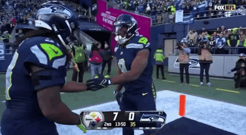 two seahawks players are shaking hands on the field during a fox nfl game