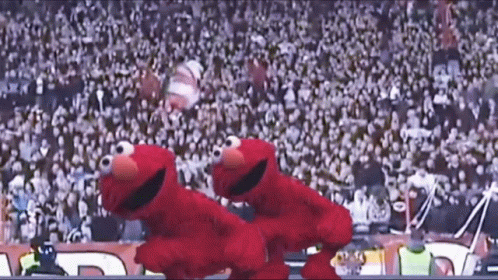 Two Sesame Street Characters Are Dancing In Front Of A Crowd At A Stadium GIF