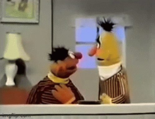 Two Sesame Street Characters Are Standing Next To Each Other In A Living Room . GIF