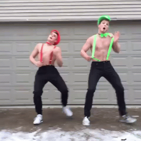 Two Shirtless Men Are Dancing In Front Of A Garage Door Wearing Suspenders And A Green Bow Tie . GIF