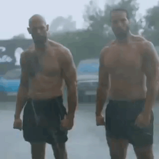 Two Shirtless Men Are Standing In The Rain Holding Hands . GIF