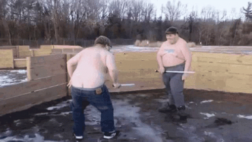 Two Shirtless Men with Swords at Wooden Fence