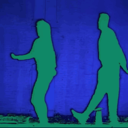 Two Silhouettes Of A Man And A Woman Walking In Front Of A Blue Wall GIF