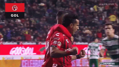 Two Soccer Players Are Celebrating A Goal In Front Of A Crowd GIF