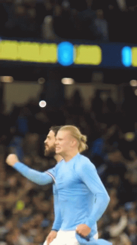 Two Soccer Players Are Celebrating A Goal In Front Of A Scoreboard That Says Manchester City GIF