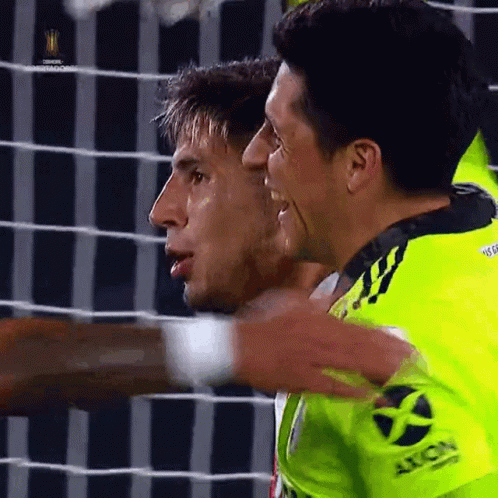 Two Soccer Players Are Hugging Each Other And One Has The Word Axion On His Sleeve GIF