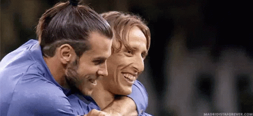 Two Soccer Players Are Hugging Each Other And Smiling . GIF