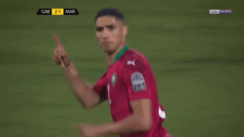 two soccer players are hugging each other on a field with bein sports on the screen behind them