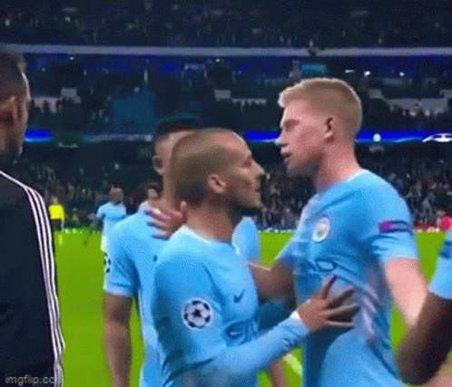 Two Soccer Players Are Hugging Each Other On The Field . GIF