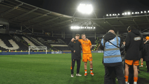 Two Soccer Players Are Posing For A Picture On A Field With A No Sweat Advertisement In The Background GIF