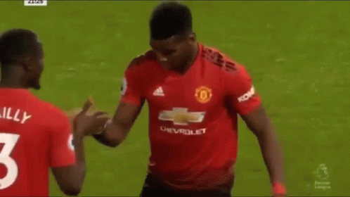 Two Soccer Players Are Shaking Hands On The Field During A Match . GIF