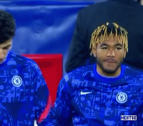 Two Soccer Players Are Shaking Hands On The Field While Wearing Blue Jerseys . GIF