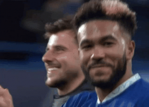 Two Soccer Players Are Smiling And Clapping Their Hands While Standing Next To Each Other . GIF