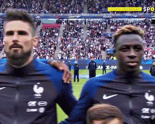 Two Soccer Players Are Standing Next To Each Other On A Field . GIF
