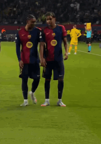 Two Soccer Players Are Walking On The Field And One Has A Spotify Logo On His Jersey GIF