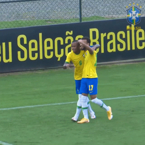 Two Soccer Players Celebrate in Front of Selecao Brasile Sign