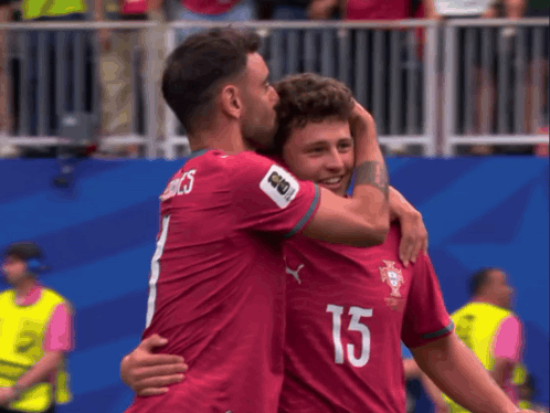 two soccer players hugging each other with one wearing the number 15
