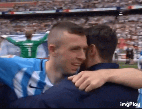 Two Soccer Players Hugging in Stadium With Number 1 on Jersey