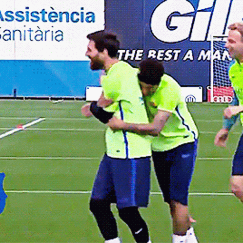 Two Soccer Players Hugging On A Field With A Sign That Says ' Assistance Sanitaria ' In The Background GIF