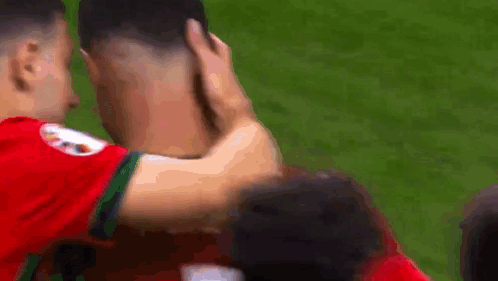 Two Soccer Players Hugging, One Touching Head