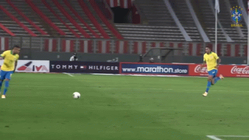 Two Soccer Players on Field with Tommy Hilfiger Ad