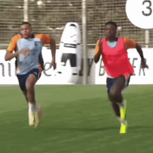 two soccer players running on a field with the number 3 behind them
