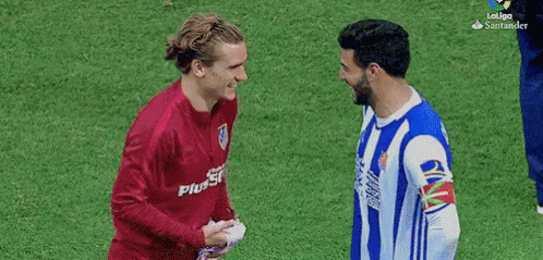 Two Soccer Players Shaking Hands One in Plus500 Shirt