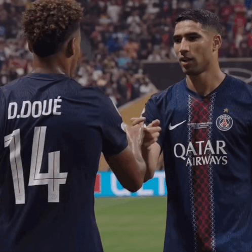 two soccer players shaking hands with one wearing the number 14