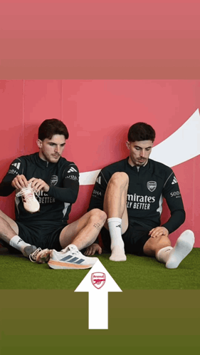 Two Soccer Players Sitting, One Wearing Emirates Fly Better