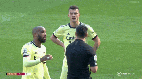 Two Soccer Players Talk Referee in Emirates Jerseys