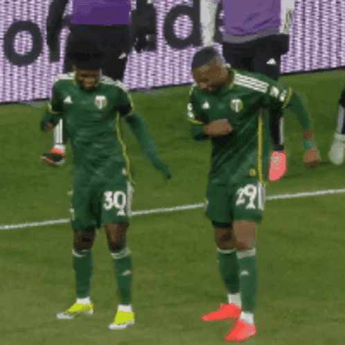 Two Soccer Players Wearing Green Jerseys With The Number 30 And 29 GIF