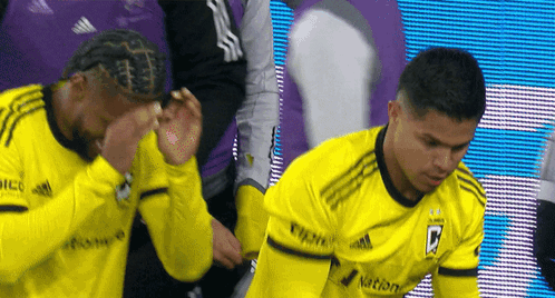 Two Soccer Players Wearing Yellow Jerseys With The Letter B On The Front GIF