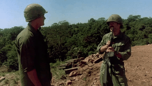 Two Soldiers in Front of a Thatched Hut With Explosion