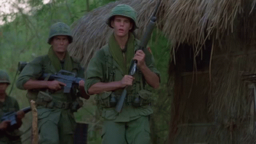 Two Soldiers in Front of Thatched Hut With Explosion